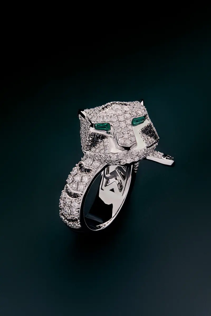 Anillo con forma de tigre en oro blanco de 18K con diamantes blancos y negros en talla brillante con un total de 2,12 cts y 2 esmeraldas en talla trapecio con un total de 0,13 cts