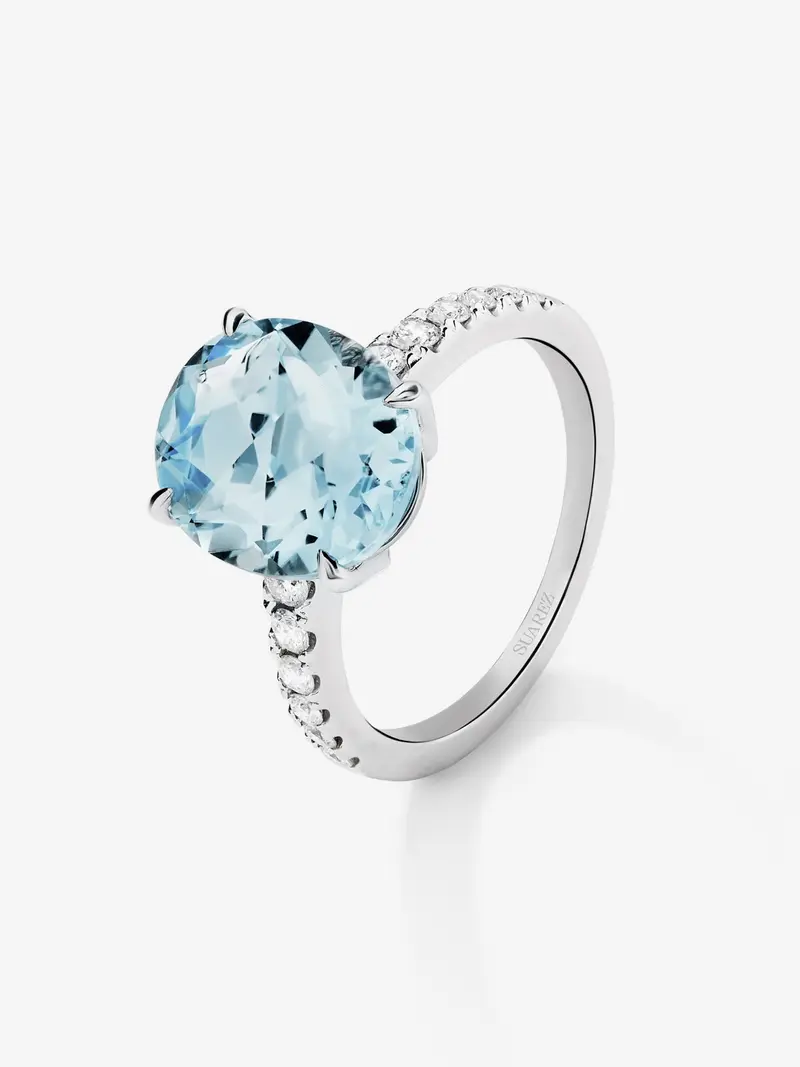 Anillo de oro blanco de 18K con topacio azul sky en talla oval de 5,8 cts y 12 diamantes en talla brillante con un total de 0,3 cts