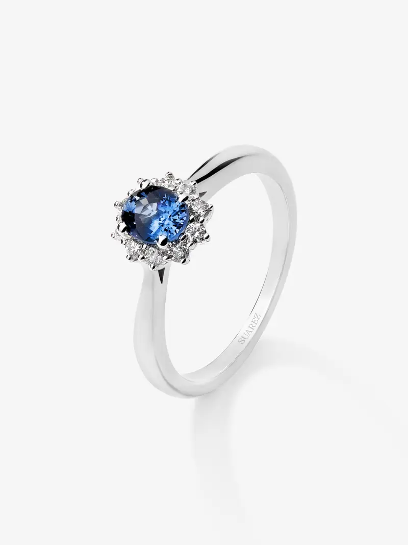 Anillo de oro blanco de 18K con zafiro azul central en talla oval de 0,40 cts y orla de diamantes en talla brillante