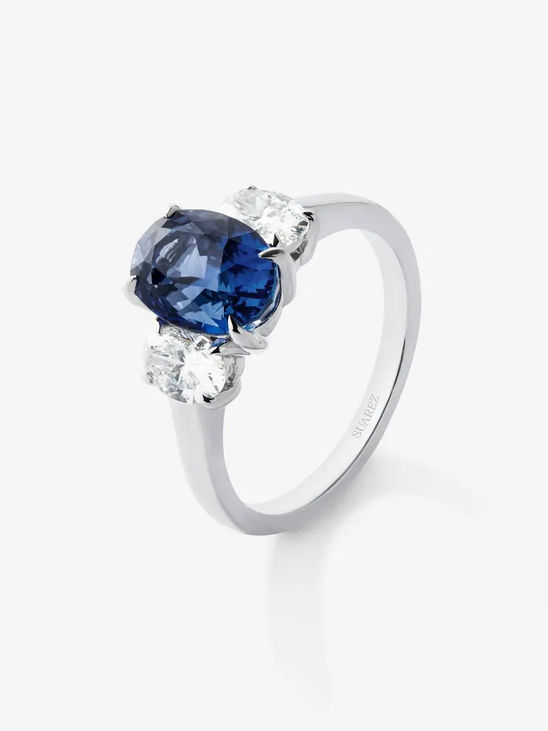 Anillo tresillo de oro blanco de 18K con zafiro azul royal en talla oval de 3,37 cts y 2 diamantes en talla oval con un total de 0,8 cts