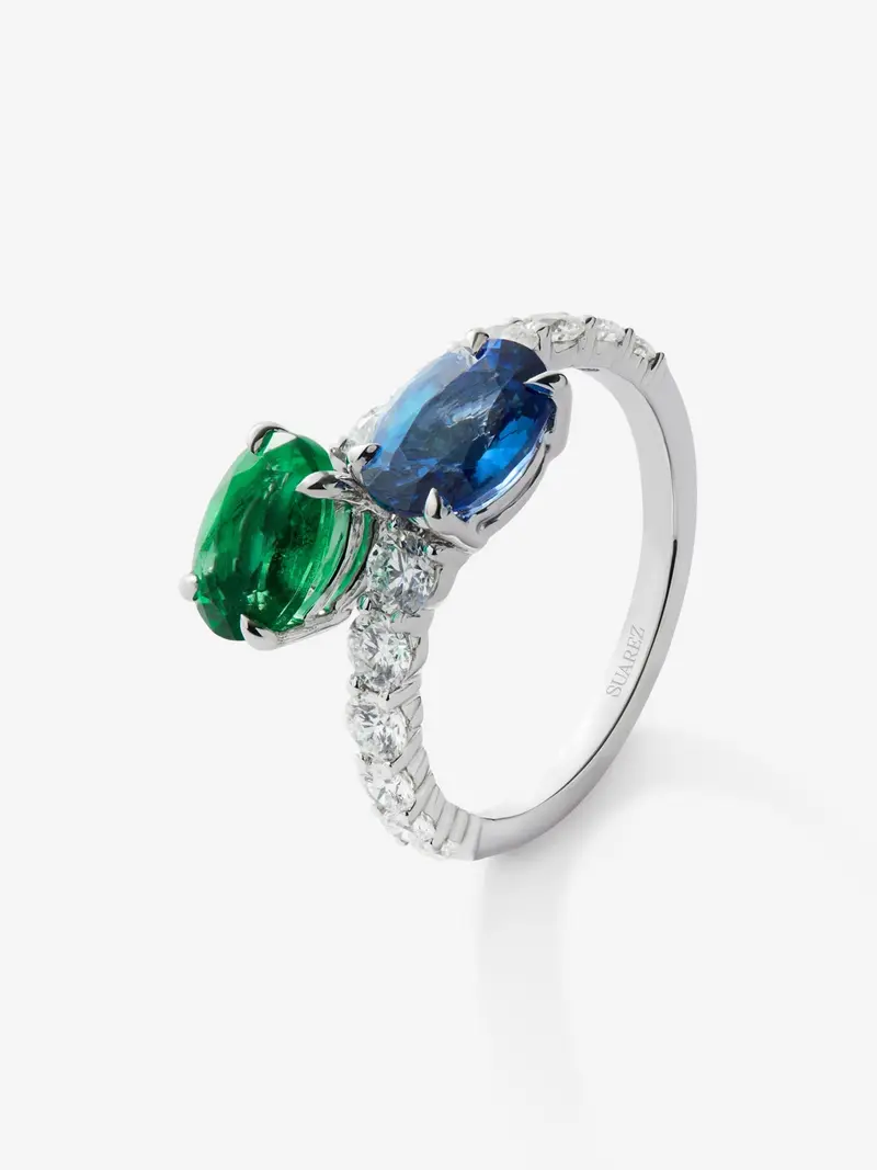 Anillo tú y yo de oro blanco de 18K con zafiro azul en talla oval de 1,75 cts, esmeralda en talla oval de 1,28 cts y 12 diamantes en talla brillante con un total de 0,25 cts