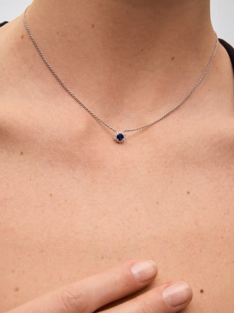 Colgante de oro blanco de 18K con un zafiro azul en talla brillante de 0,37 cts y 10 diamantes en talla brillante con un total de 0,14 cts con forma de estrella