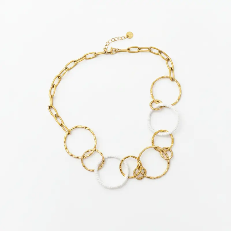 Collar de acero de aros con texturas y con hilo blanco y en acabado oro