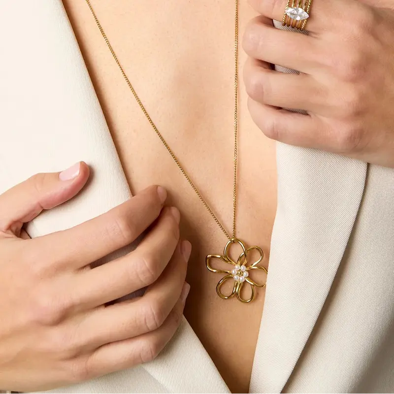 Collar largo de acero con dije mediano de flor y perlas acabado oro