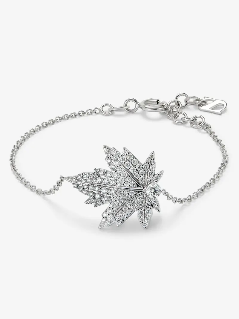 Pulsera de oro blanco de 18K con diamante central en talla brillante de 0,14 cts, pavé de diamantes y forma de hoja de arce