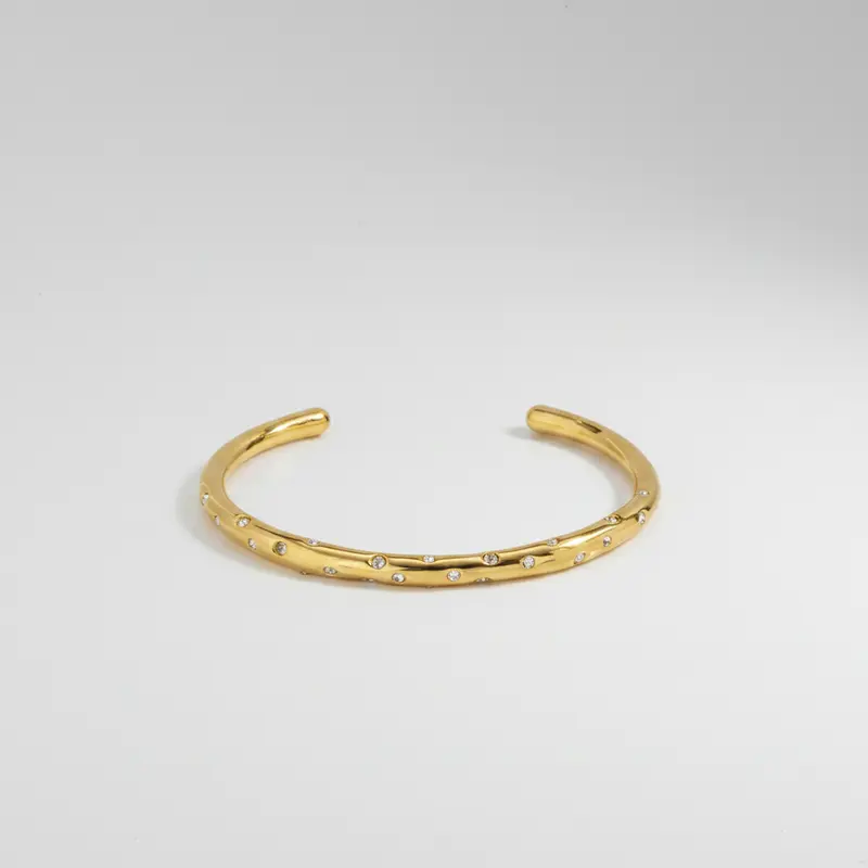 Pulsera rígida circonitas en posiciones aleatorias y en acabado oro