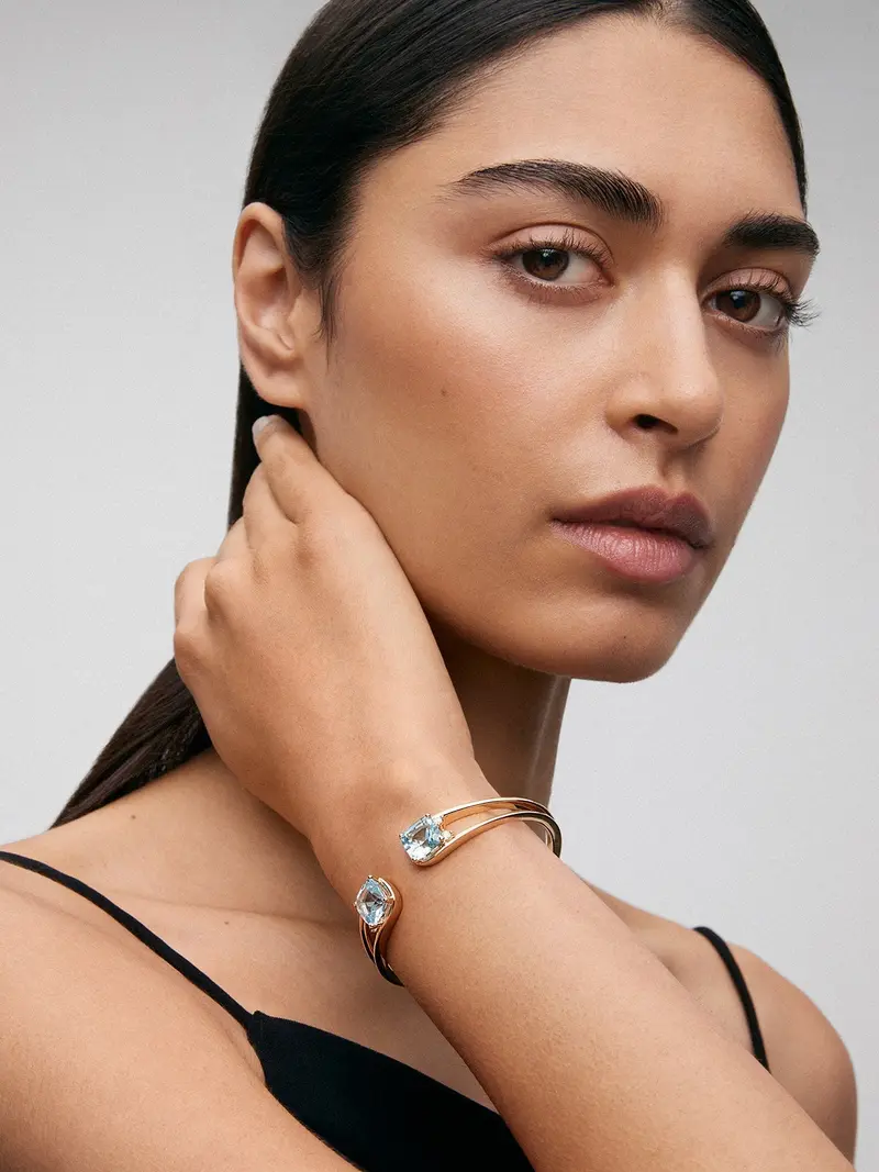 Pulsera rígida de oro amarillo de 18K con 2 topacios azul sky en talla cushion con un total de 0,12 cts